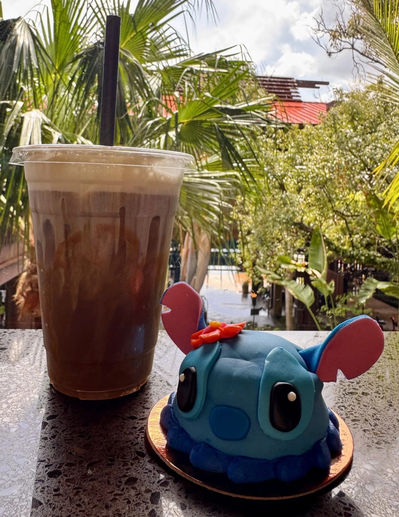 Stitch dome cake and iced Kona blend coffee with Polynesian Village Resort palm trees in the background