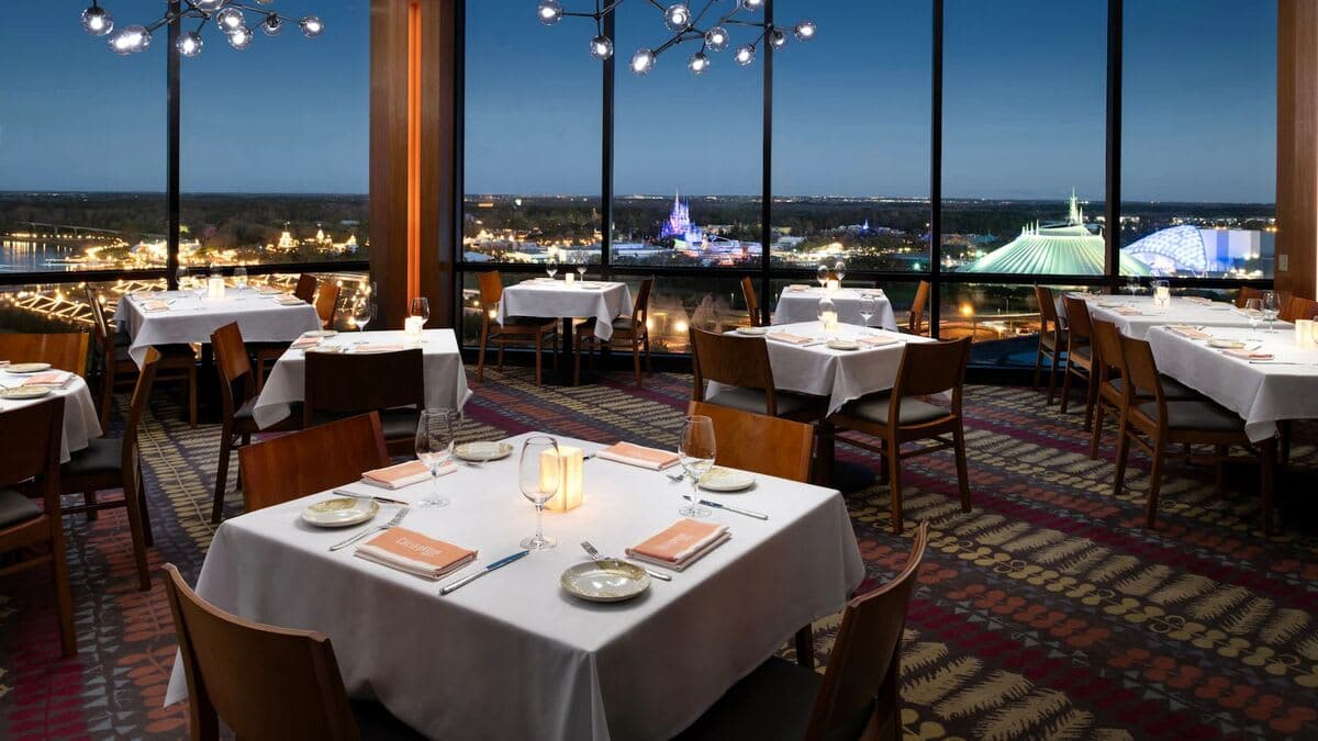 California Grill dining room at Disney's Contemporary Resort with floor-to-ceiling windows overlooking Magic Kingdom, Cinderella Castle, and Space Mountain at night
