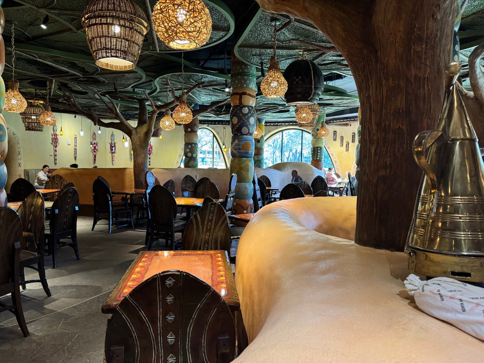 The dining room at Sanaa restaurant at Kidani Village with tree-shaped columns, woven globe lanterns, and arched windows overlooking the savanna
