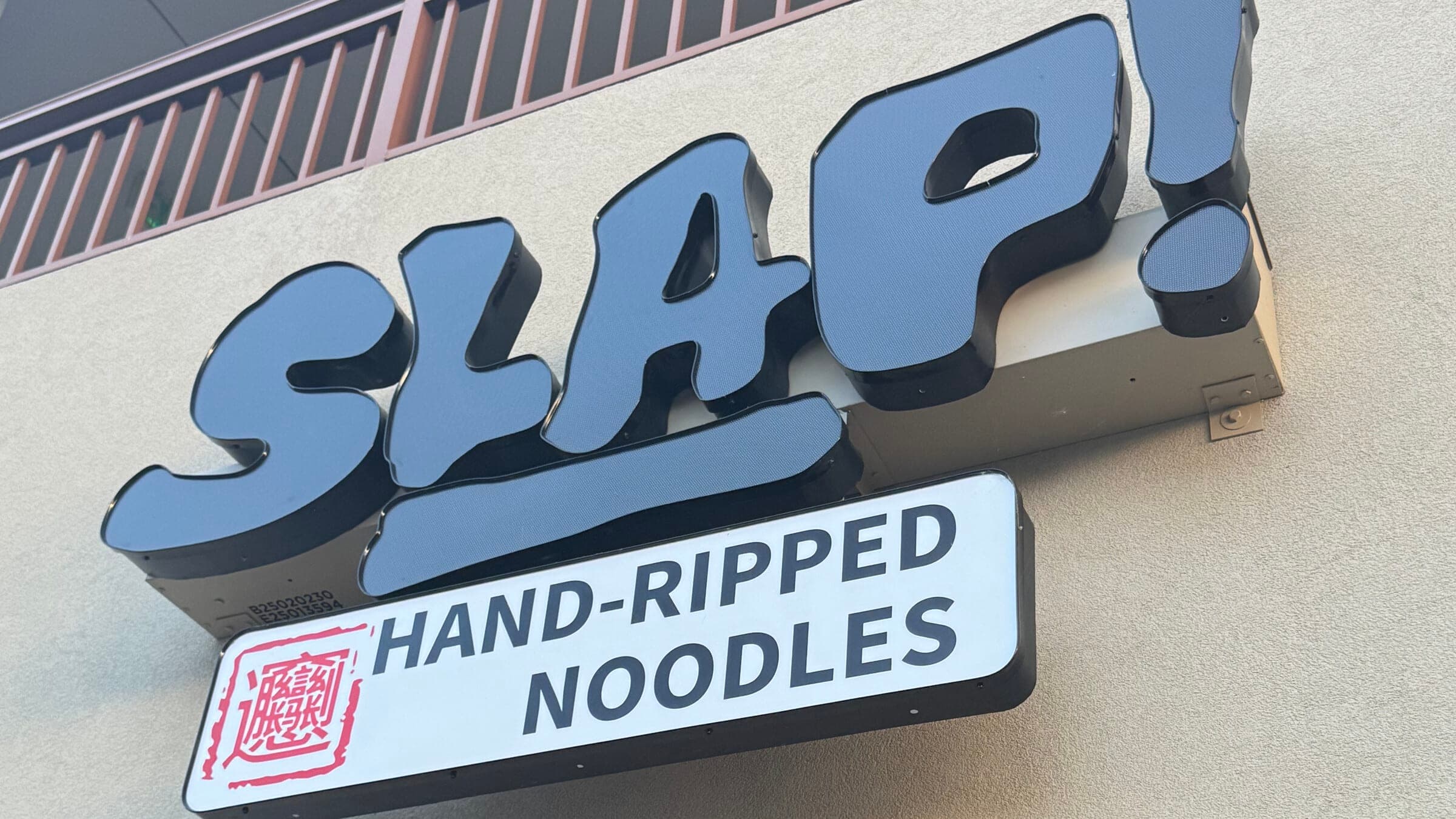 SLAP Hand-Ripped Noodles black storefront sign in Dowdy Plaza on Carrier Drive in Orlando Florida