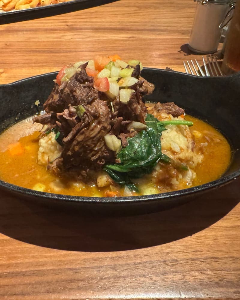 Slow-braised shredded pot roast over creamy mashed potatoes with sautéed greens and fresh vegetable relish in a rich brown gravy